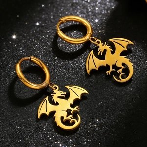 Gros plan de boucles d'oreilles dragon dorées avec ailes ciselées sur fond noir étoilé