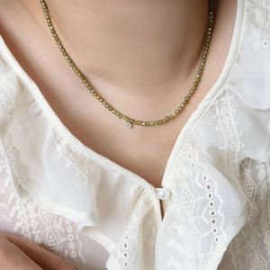 Detail of green zircon beaded necklace on lace collar showing elegant craftsmanship