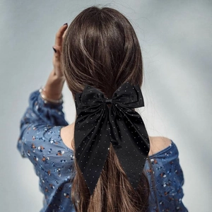Barrette nœud noire surdimensionnée avec pois argentés sur cheveux bruns