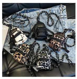 Flat lay of mini crossbody bags in leopard, zebra, and cow prints on denim fabric