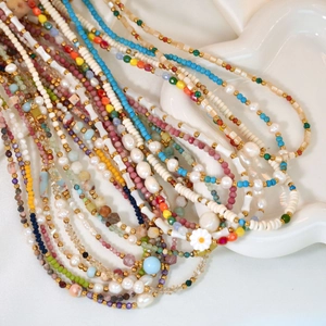 Detailed shot of handmade pearl and colorful crystal beaded necklace on a white cloud tray