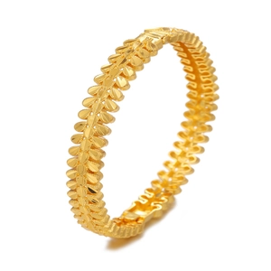 Macro detail of gold flower hollow cuff bracelet with leaf patterns and matte texture