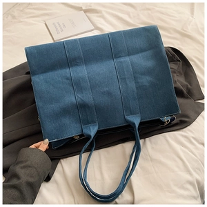Detail view of large denim tote bag featuring white contrast stitching and durable fabric