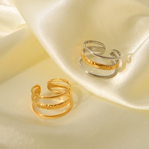 Detailed view of layered 18K gold and silver textured rings on elegant cream silk fabric