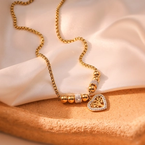 Gold tree of life heart necklace with sparkling zircons on elegant silk background