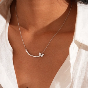 Detailed view of silver butterfly necklace with pearls and zircon inlay on neck