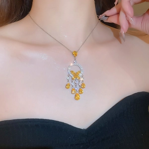 Detail shot of yellow crystal butterfly pendant necklace on a model with silver chain