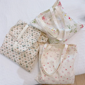 Detailed view of three cotton tote bags with different floral patterns on textured fabric