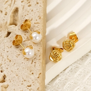 Élégantes boucles d'oreilles roses dorées et perles blanches sur fond en pierre chaude