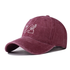 Macro detail of washed cotton baseball cap with embroidered coconut tree in dark red