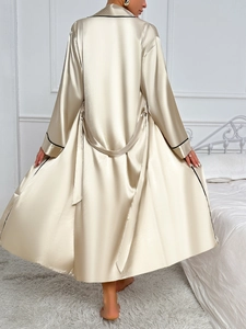Macro view of long champagne satin robe showing smooth fabric texture and black piping detail