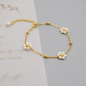 Macro shot of 18K gold plated flower bracelet with white pearls and adjustable chain