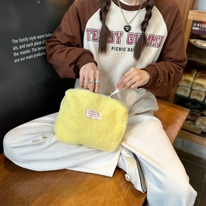 Detail of soft yellow faux shearling makeup bag with zipper and woven label in a bakery