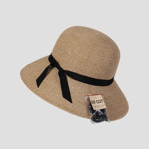 Detail of woven straw hat featuring UV cut label and elegant black grosgrain ribbon bow
