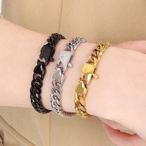 Close-up of gold, silver and black stainless steel Cuban link bracelets worn on wrist