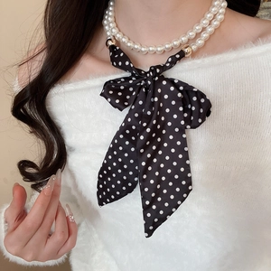 Close-up of double-layer pearl necklace with black polka dot silk bow on model