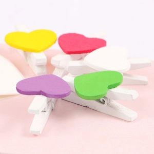 Mini wooden heart clips in various colors on pink background for Valentine decor