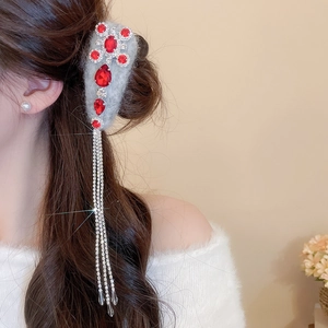 Detail of grey flocked hair clip with red water-drop rhinestones and long silver tassels