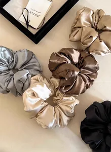 Macro shot of assorted silk satin scrunchies in silver, gold, and brown tones