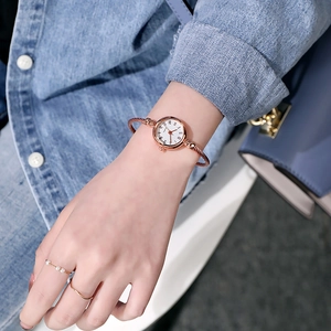 Detail of rose gold bangle watch with white Roman dial on a woman's wrist
