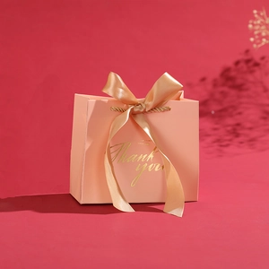 Pink paper wedding favor bag with gold Thank You text and a satin ribbon bow