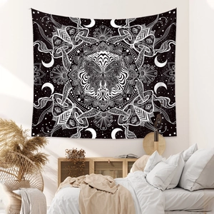 Black and white psychedelic tapestry hanging in a cozy bedroom with bohemian decor