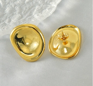 Macro detail of irregular oval gold-plated stainless steel earrings on grey fabric