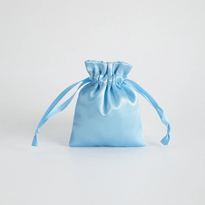 Detailed view of the sky blue satin drawstring bag for jewelry storage on white background