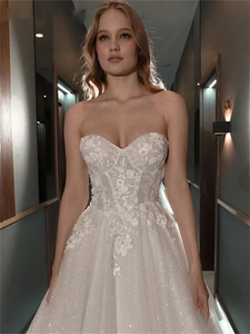 Detail of white off-shoulder wedding dress with floral lace and shimmering glitter fabric