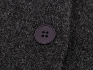 Macro shot of charcoal grey knit wool fabric with a brown resin button detail
