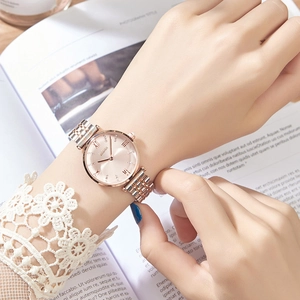 Close-up of stylish two-tone metal watch with rose gold dial worn on a female wrist