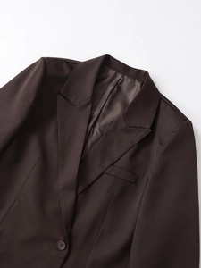 Dettaglio del blazer marrone scuro con revers a lancia e trama del tessuto pregiato