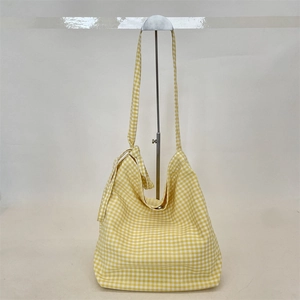 Detail of yellow gingham canvas tote bag with knotted strap on a metal stand