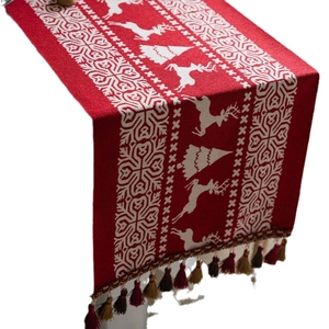 Red Christmas table runner with white reindeer and snowflake patterns and tassels