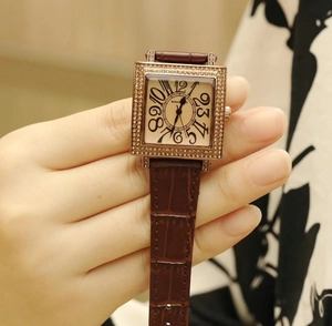 Primer plano de reloj cuadrado para mujer con bisel de diamantes y correa de cuero