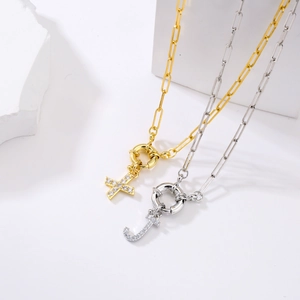 Vue macro de la croix dorée et du pendentif lettre J sur colliers maille trombone