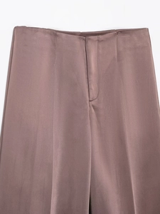 Detail of elegant dusty rose satin trousers with hidden fly and smooth silk texture