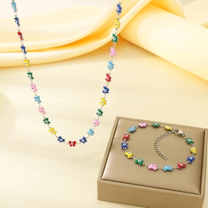 Detail of colorful enamel butterfly and evil eye charms on gold chain necklace and bracelet