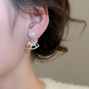 Elegant pearl stud earring with pink enamel rocking horse pendant on a female model