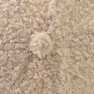 Close-up of beige fleece baseball cap featuring plush lamb wool texture and pom-pom detail