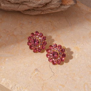 Detail shot of pink rhinestone flower studs on a textured beige stone background