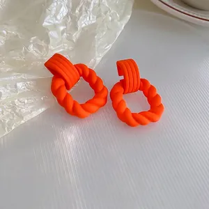 Boucles d'oreilles créoles orange mat avec tige en argent sur fond blanc moderne