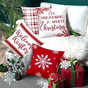 Set of four red and white Christmas pillow covers with snowflakes on a white sofa