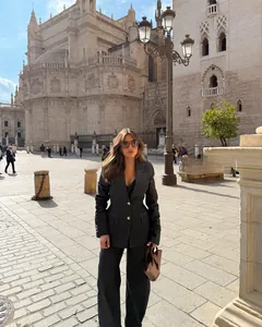 Detalle de blazer gris oscuro con botones dorados y pantalones de pernera ancha de talle alto