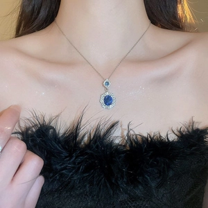 Close-up of elegant oval blue gemstone necklace with diamond accents on a model