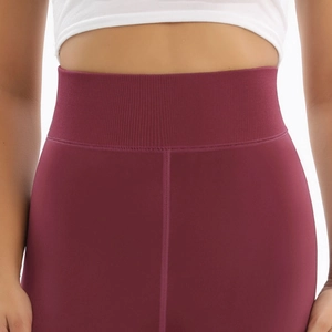 Macro view of burgundy high-waisted leggings with ribbed waistband and flatlock seams