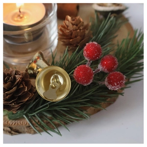 Close-up of Christmas wooden candle holder with gold bells, pine cones and red berries