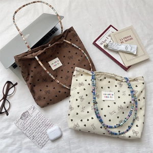 Detailed view of corduroy tote bags with colorful beaded handles and heart bow prints