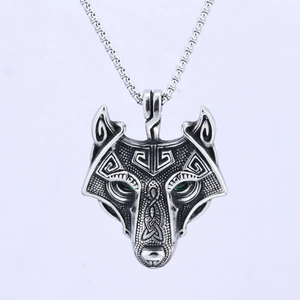 Macro shot of silver wolf head pendant with green eyes and detailed Nordic engraving