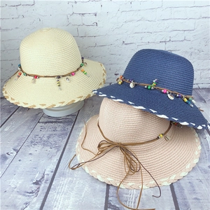 Detail of three colorful straw hats with decorative shells and bohemian beads